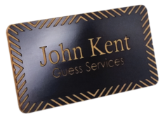 A square and brown Engraved Name Badge with the leyend: "John Kent, Guests Services"